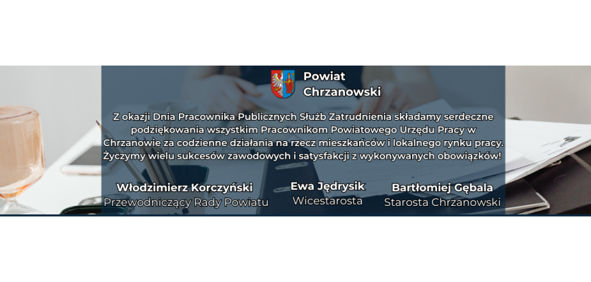 Baner ze zdjęciem w tle, na którym widać biurko z szeregiem dokumentów, telefonem i ołowkami. Na środku pole tekstowe z herbem powiatu.