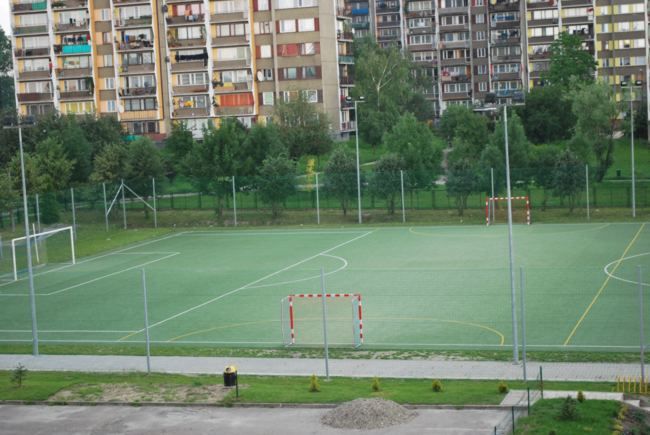 widok na boisko o nawierzchni trawiastej wokól bloki os. niepoldegłosci, na boisku wyrysowane linie, rozmieszczone bramki