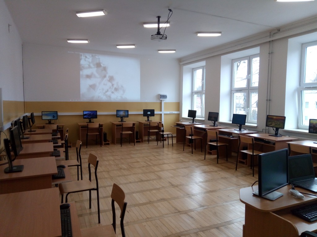 sala lekcyjna z ławkami i krzesłami przy stanowskikach  komputerowych  pokazany nowy parkiet na podłodze