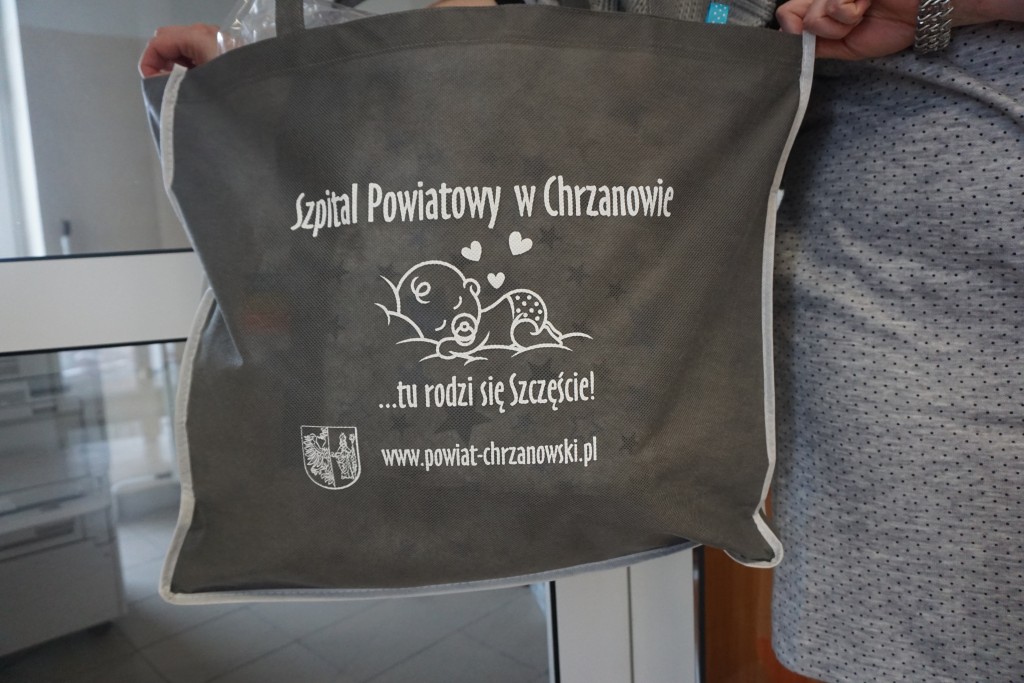 szara duża torba z białym napisem szpital powiatowy w chrzanowie tu rodzi się szczęście,grafiką niemowlaka, herbem powiatu oraz napisem www.powiat-chrzanowski.pl