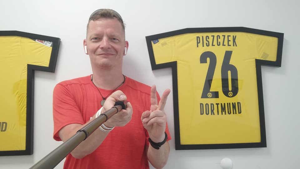 Mężczyzna robiący selfie. W tle koszulka z napisem: Łukasz Piszczek 26 Dortmund 