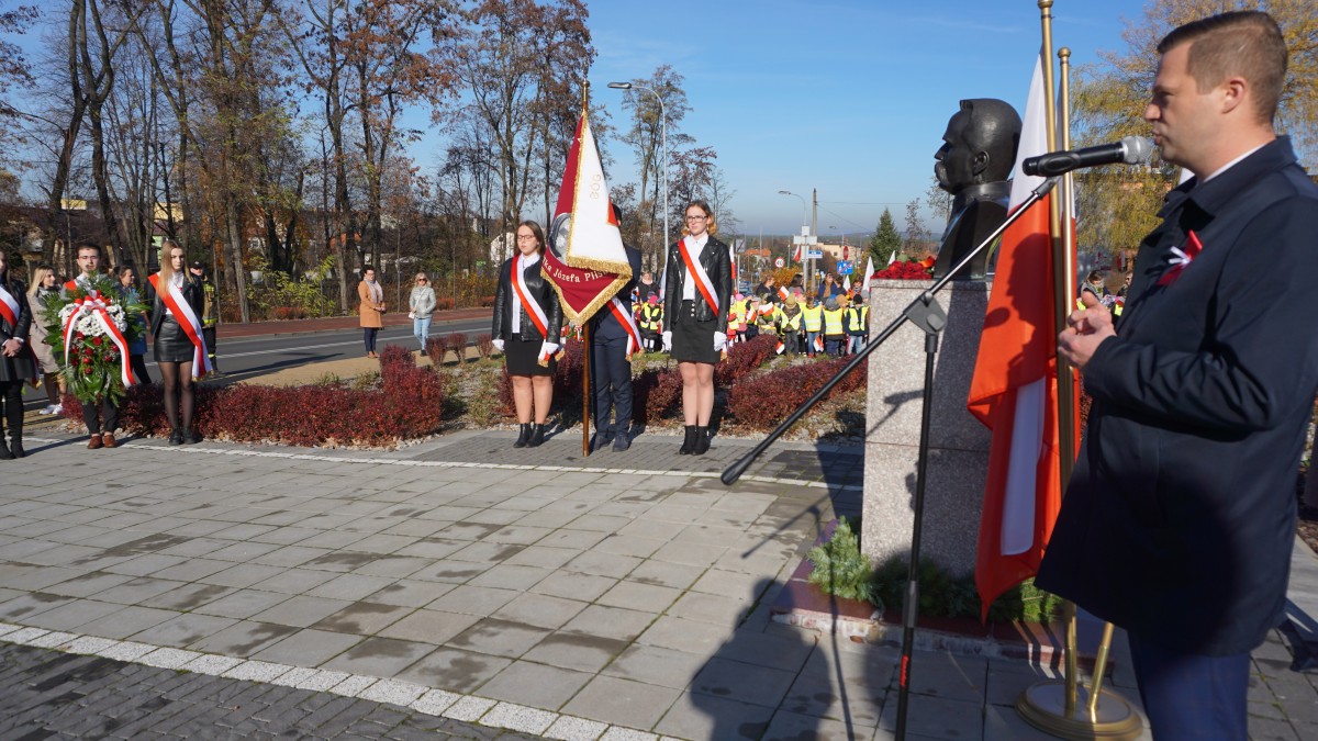 Mężczyzna w garniturze przemawia do zgromadzonych osób 