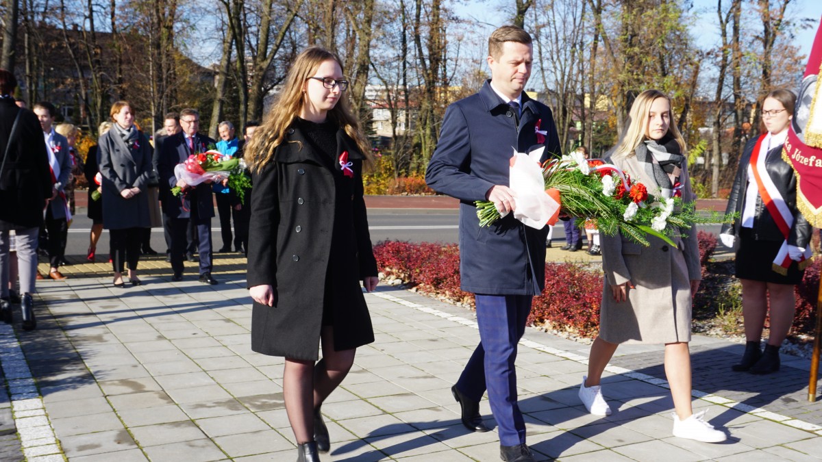 Dwie dziewczyny, mężczyzna w środku. Idą z wiązanką biało-czerwoną