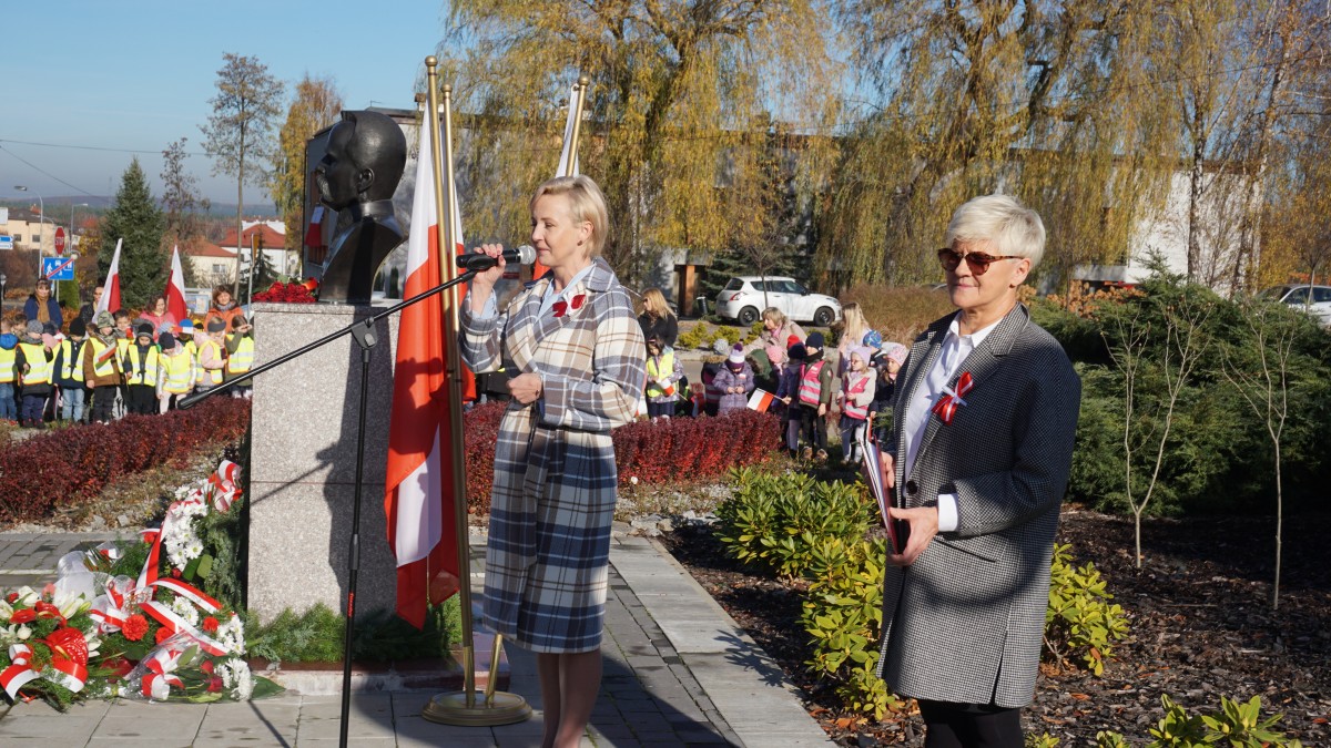 Kobieta w płaszczu przemawia do zgromadzonych