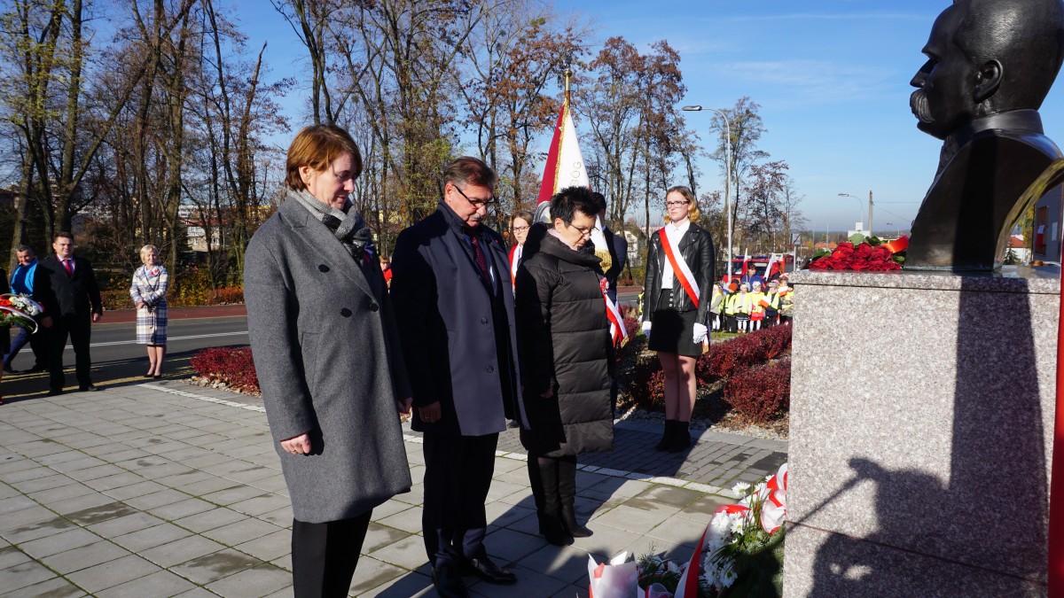 Mężczyzna i dwie kobiety stoją przed pomnikiem Marszałka Piłsudskiego 