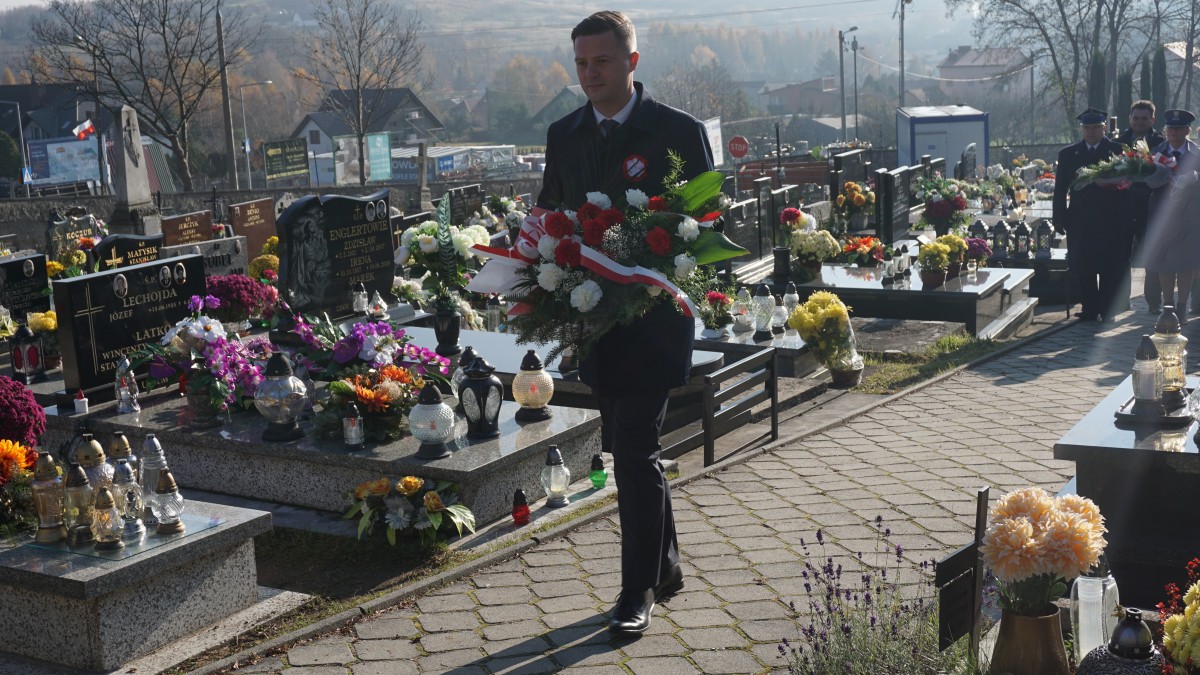 Młody mężczyzna z wiązanką kwiatów pomiędzy grobami 