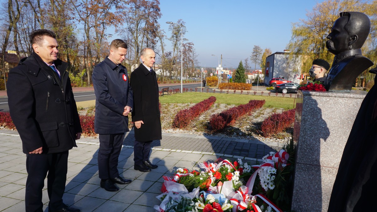 Trzech mężczyzn przed pomnikiem Marszałka Józefa Piłsudskiego 