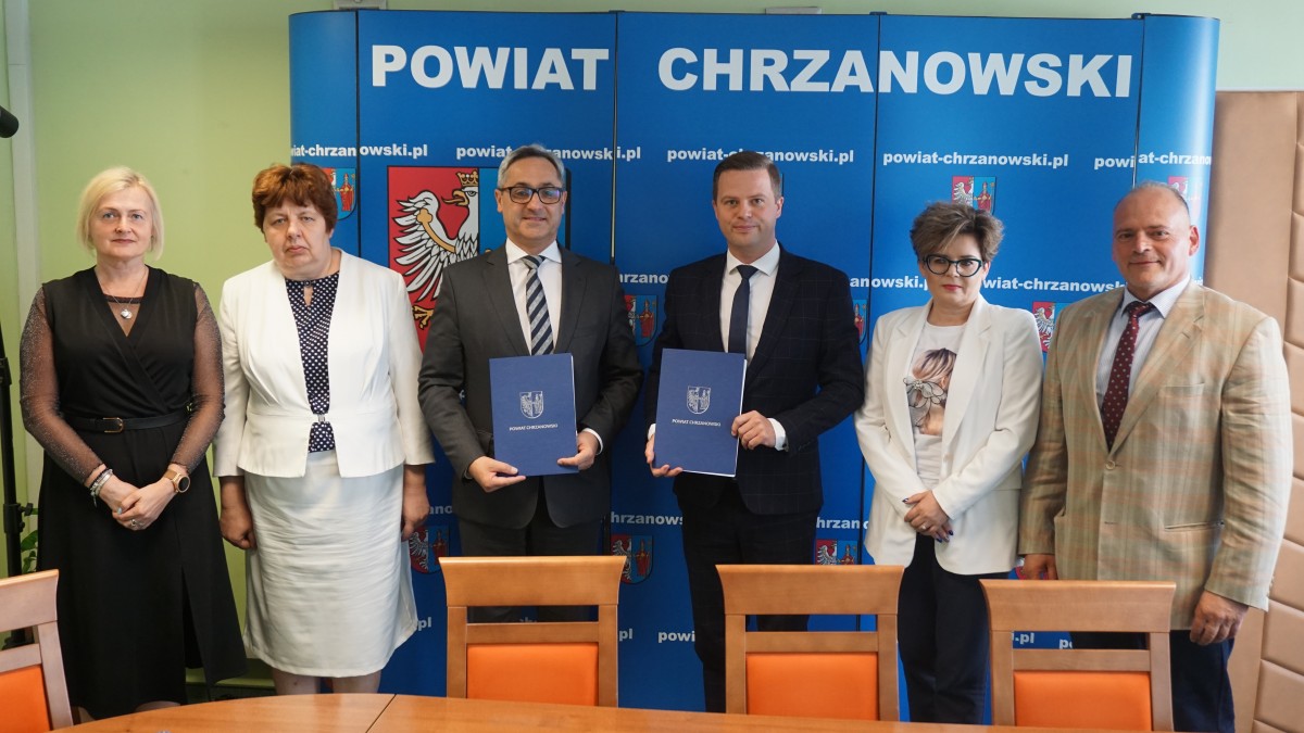 przedstawiciele powiatu wicestraosta, skarbnik, cżł. zarządu i gminy wiceburmistrz skarbnik i dyr. OPSwspólne zdjęcie przed niebieska sciianka z logo powiatu 