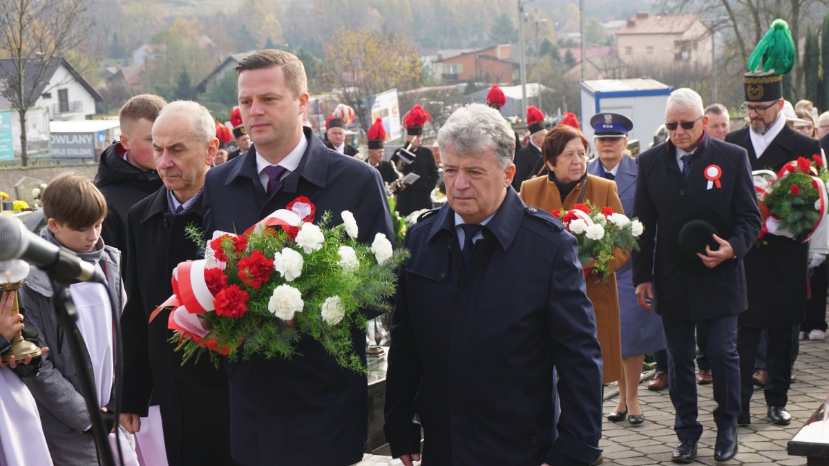 Trzech mężczyzn maszeruje z wiązanką kwiatów 