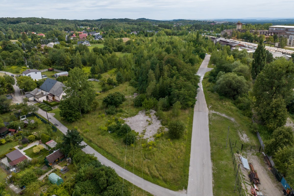 widok z lotu ptaka na ul. miłą, droga asfaltowa, wokół zieleń trawa i drzewa w oddali budynki