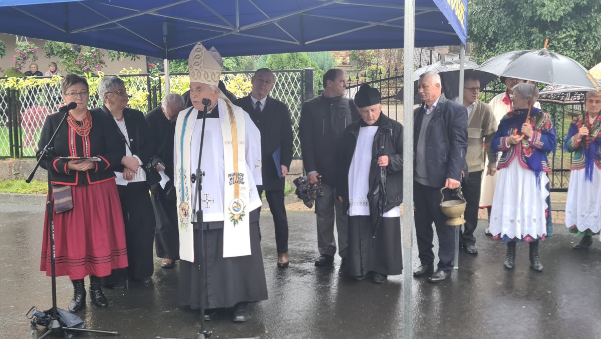Osoby zgromadzone pod zadaszeniem. Przemawia ksiądz 