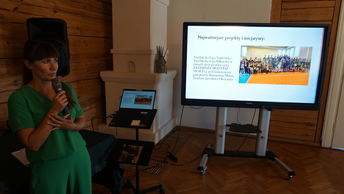 Kobieta w zielonym kombinezonie przemawia 