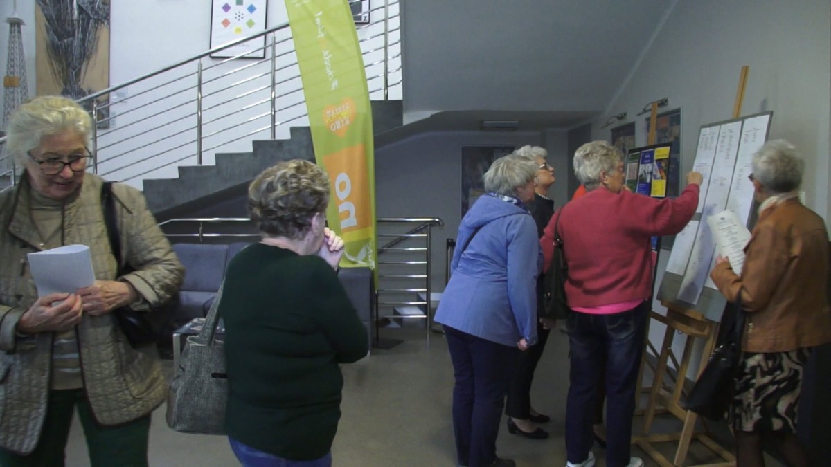 Seniorzy przed tablicą ogłoszeń