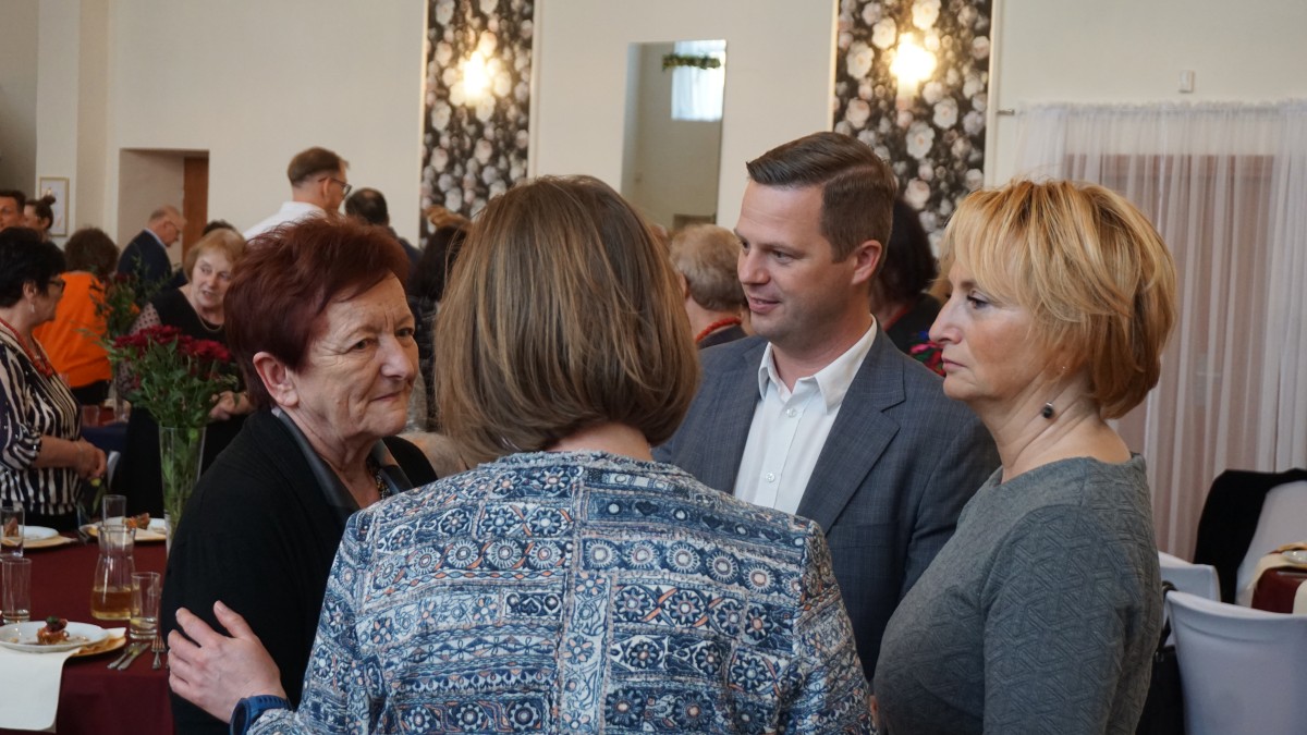 Zdjęcie 4 osób stojących i rozmawiajacych ze sobą.