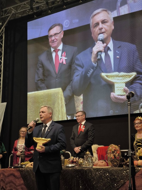 Mężczyzna na scenie, w ręku statuetka