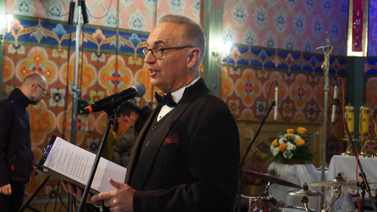 Mężczyzna w garniturze mówi do mikrofonu.