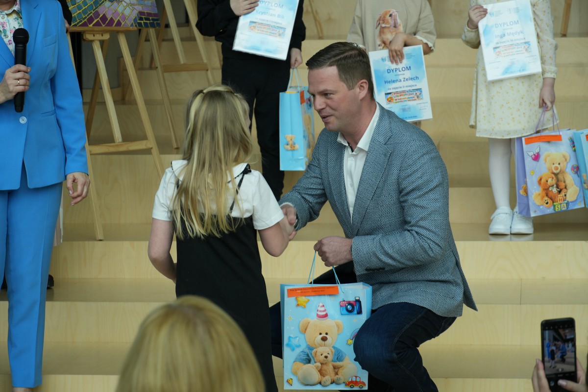 Zdjęcie Starosty wręczającego nagrody i dyplom dziewczynce. 