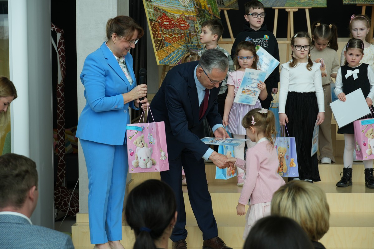 Zdjęcie Radnego wręczającego nagrody i dyplom dziewczynce. 