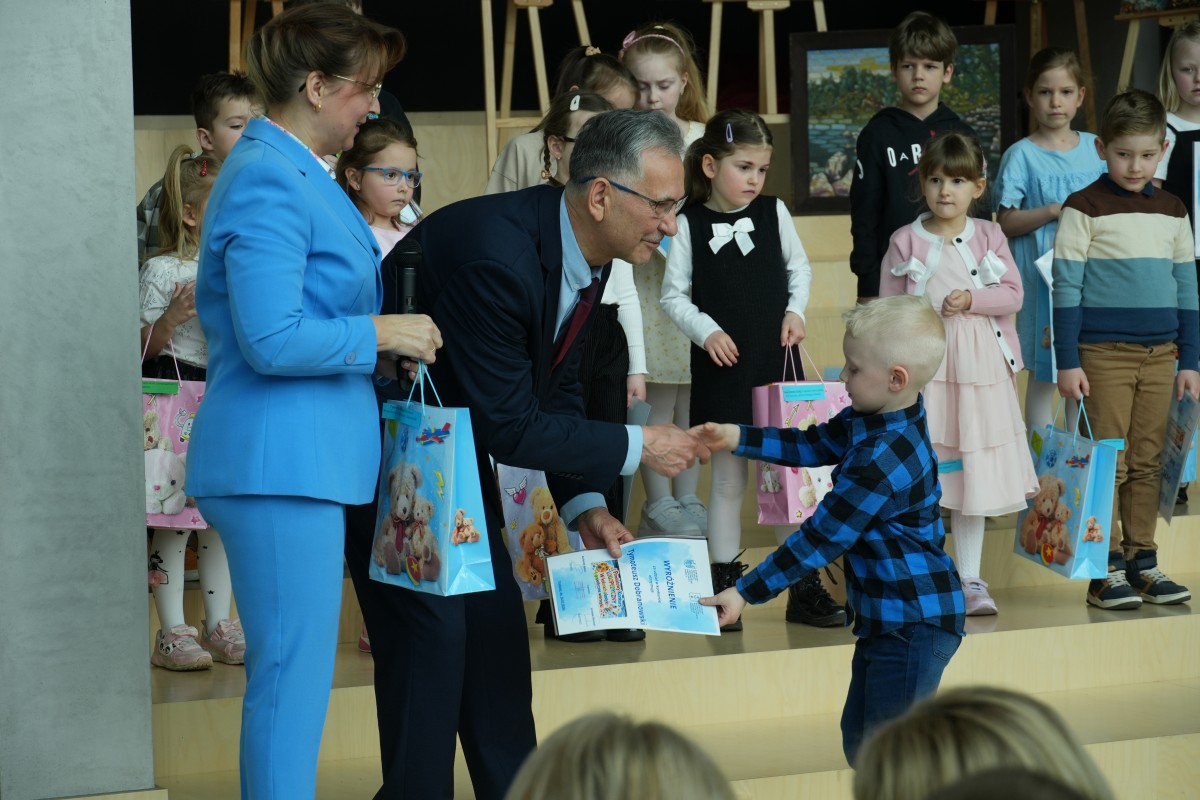 Zdjęcie Radnego wręczającego nagrody i dyplom chłopcu. 