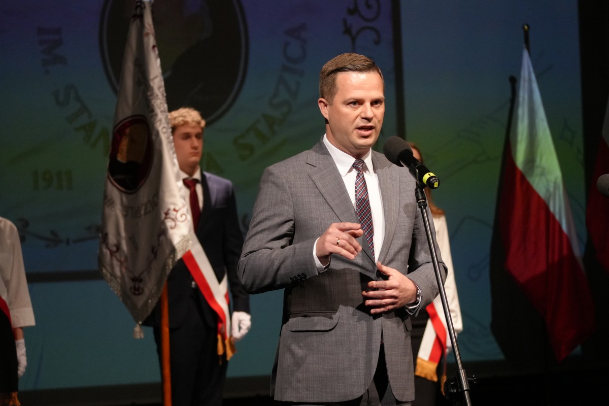 Zdjęcie Starosty przemawiajacego ze zebranych. W tle poczet sztandarowy szkoły.