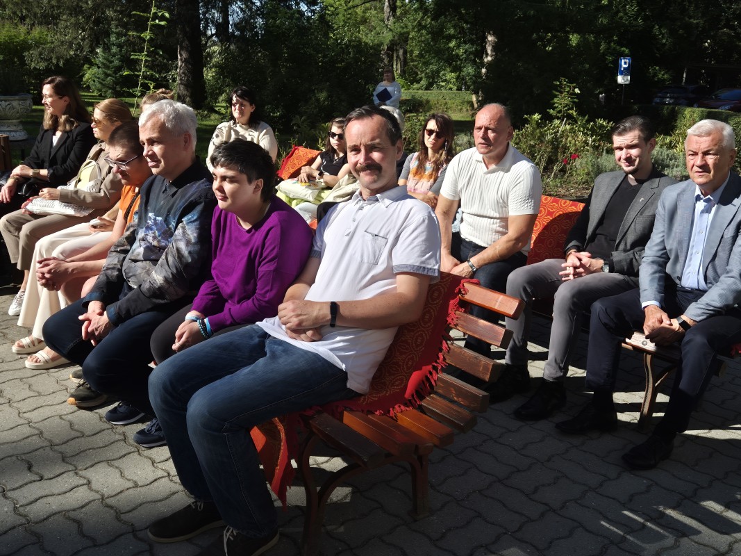 Goście i uczestnicy festiwalu siedzą na ławkach i oglądają występy