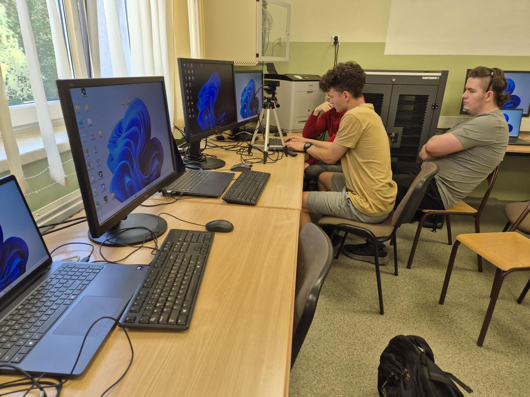 Uczniowie siedza przy komputerach w pracowni informatycznej
