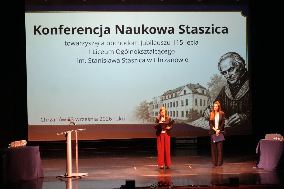 Zdjęcie dwóch kobiet stojących na środku sceny. W tle grafika tytułowa konferencji.