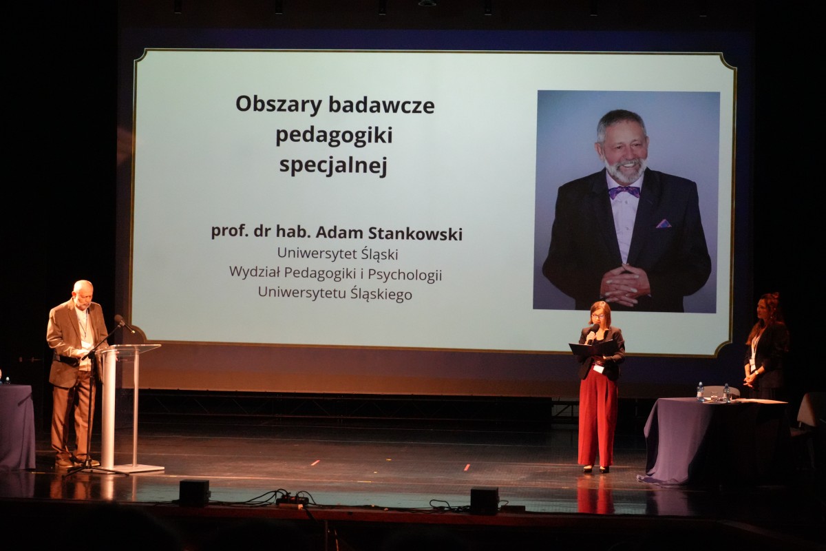 Zdjęcie mężczyzny przemawiającego zza mównicy. W tle prezentacja.