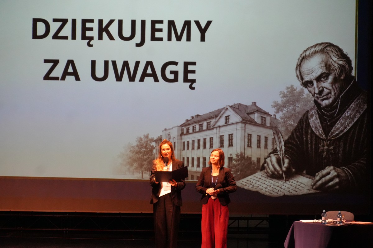 Zdjęcie dwóch kobiet stojących na środku sceny. W tle prezentacja.