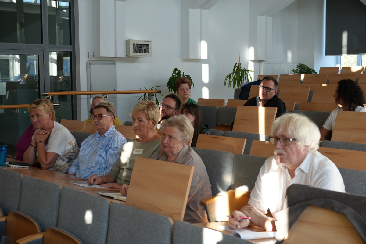 Zdjęcie kilkunastu osób siedzących na auli wykładowej.