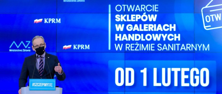 banner po lewej stronie minister zdrowia w maseczce, po prawej napis od 1 lutego otwarcie sklepów w galeriach handlowych w reżimie sanitarnym tło niebieskie w tle flagi polski i napis KPRM 