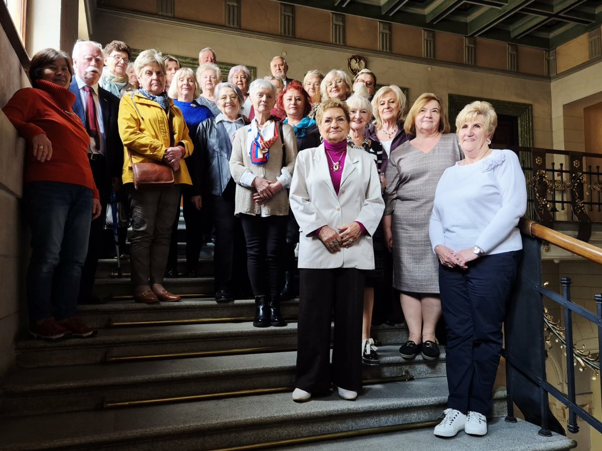 Na schodach pozują do zdjęcia kobiety i mężczyźni