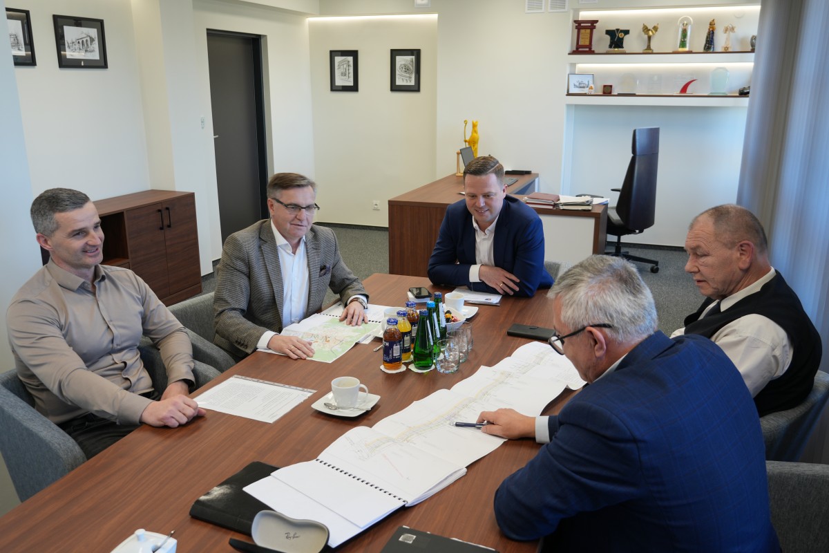 Zdjęcie pięciu mężcyzzn siedzacych przy stole. Przed nimi znajduje się kilka dokumentów. 