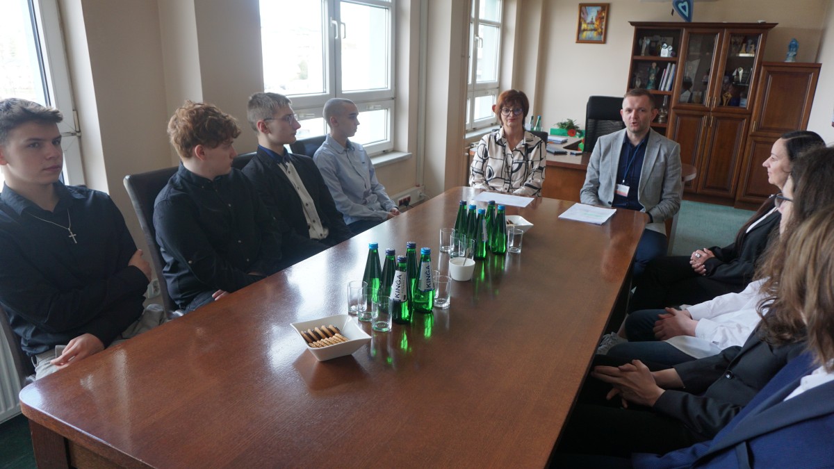 Młodzież siedzi przy stole w gabinecie wicestarosty 
