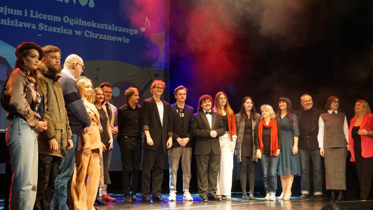 Absolwenci na scenie pozują do zdjęcia, w sumie 17 osób 