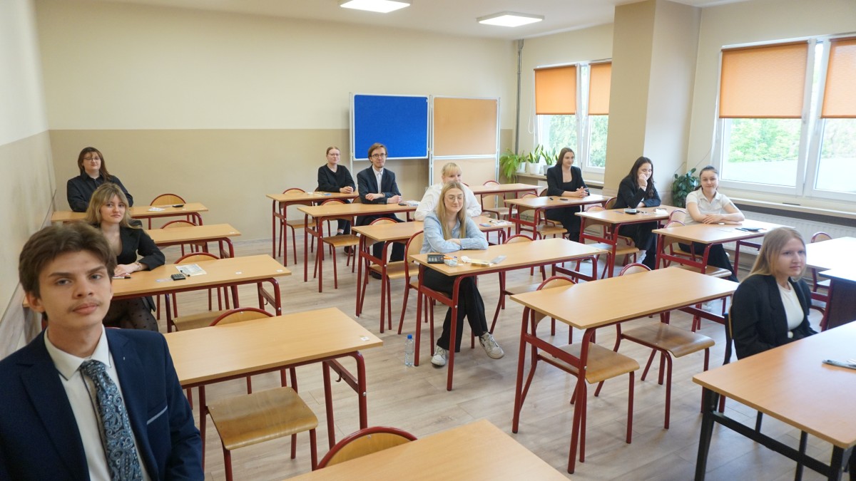 Uczniowie siedzą w ławkach 