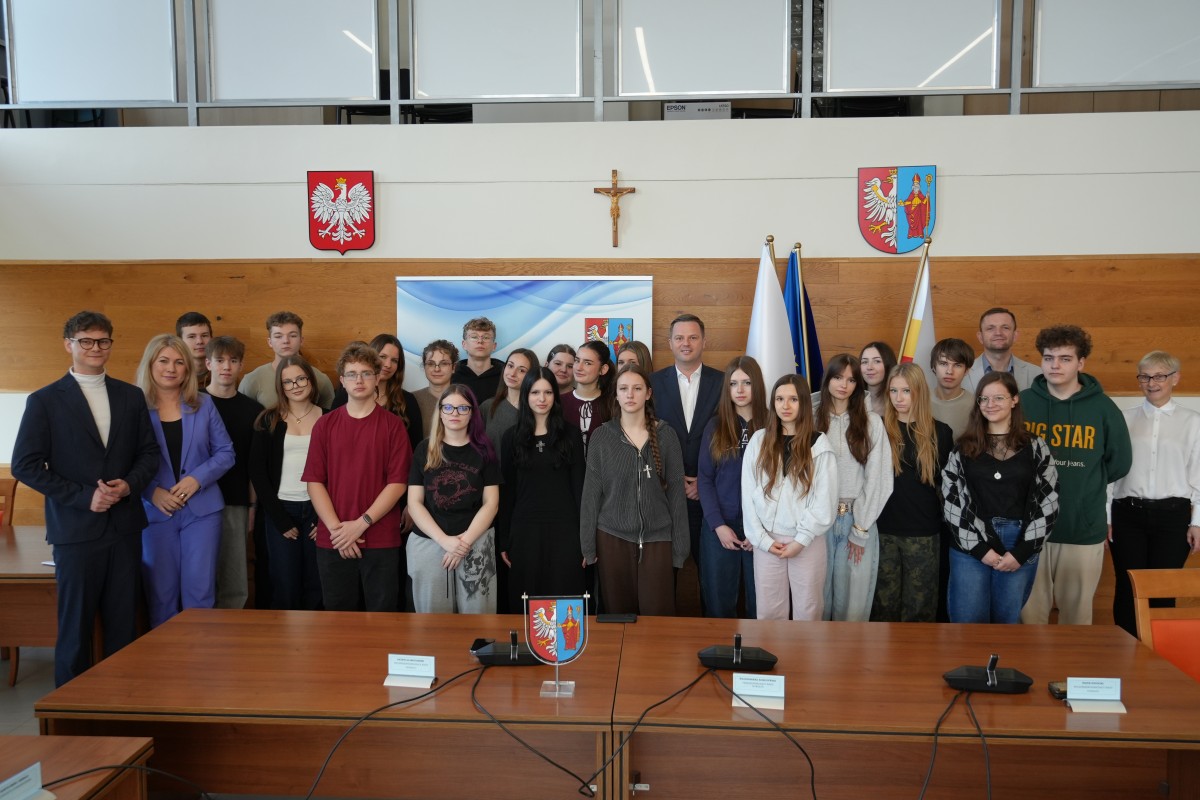 Zdjęcie kilkudziesięciu osób. Głównie uczniów, ale także kilku urzędników. W tle symbole państwowe i powiatu.