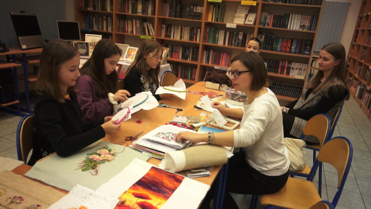 Młodzież pracuje w bibliotece z opiekunem 