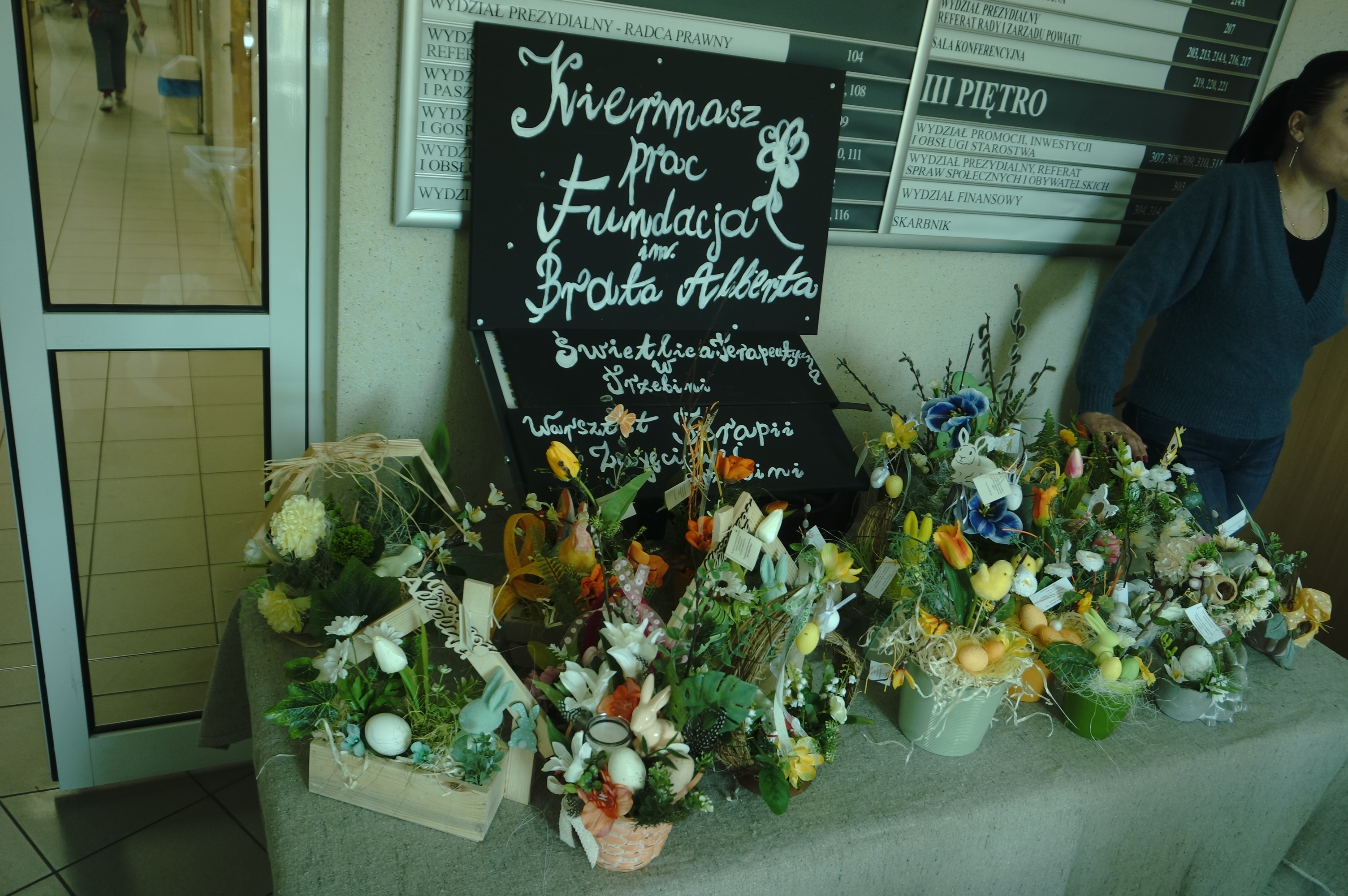 Zdjęcie wystawionych prac z rękodzieła na korytarzu wewątrz budynku