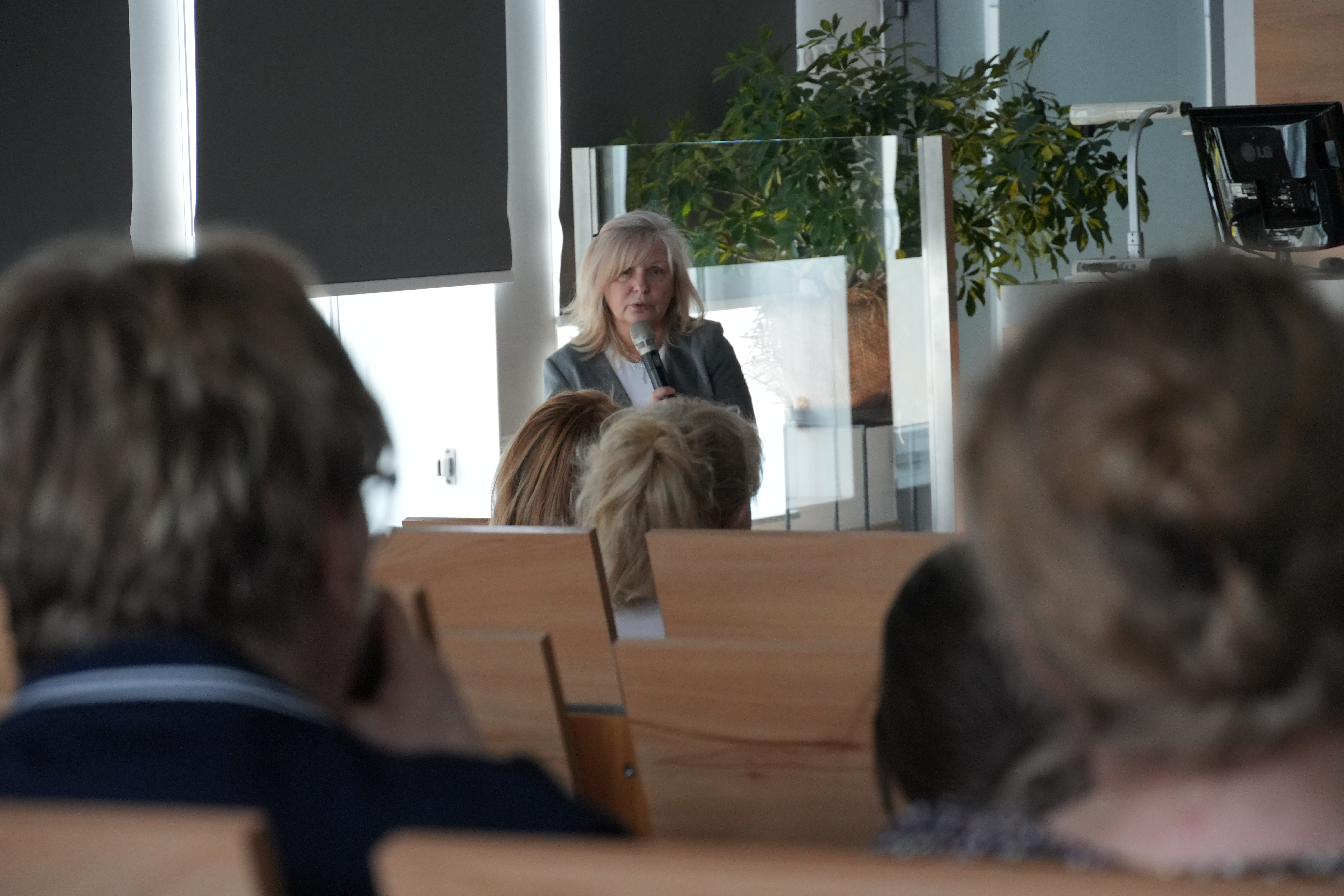 Zdjęcie kobiety trzymającej mikrofon i prowadzącej szkolenie.