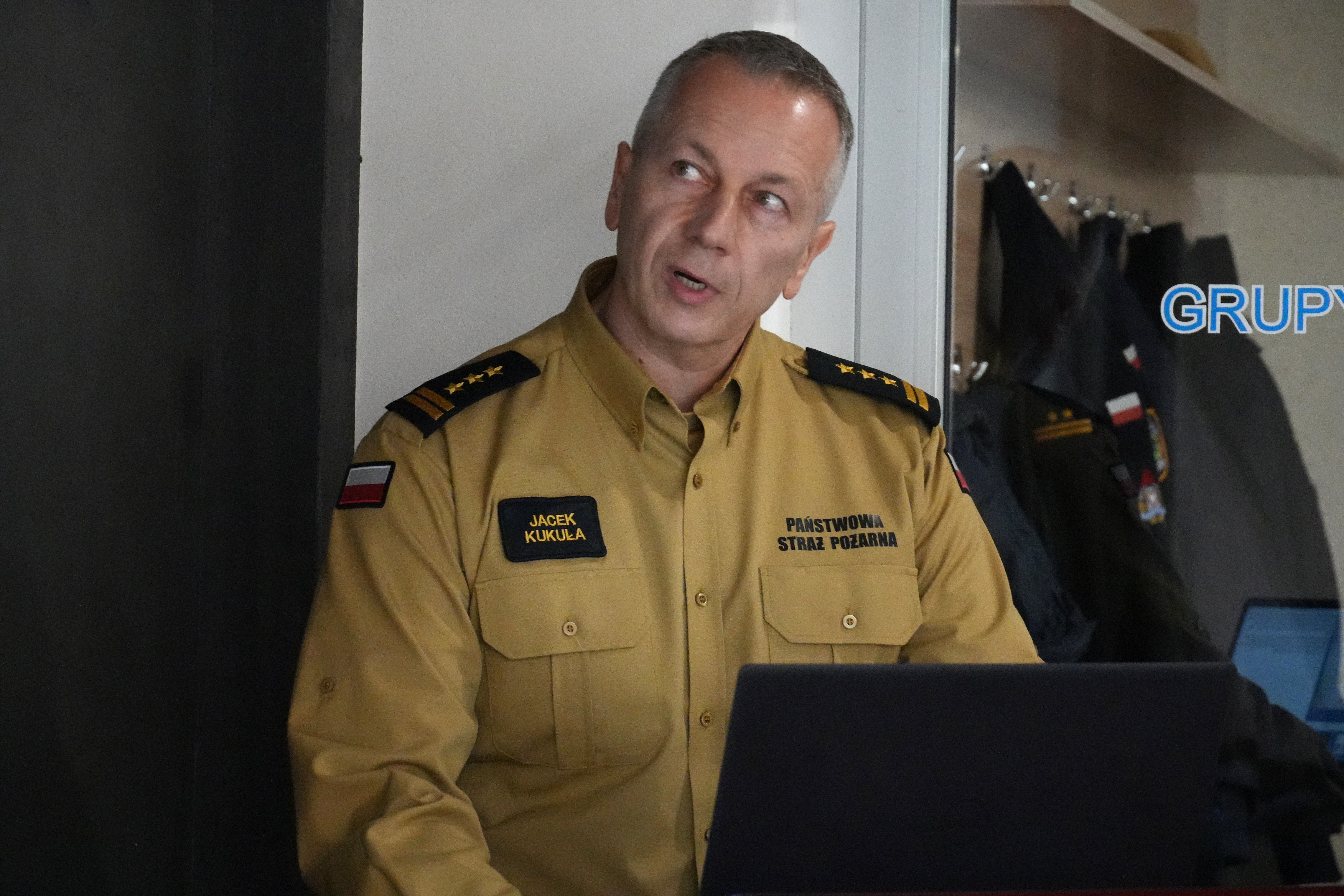 Mężczyzna w mundurze strażackim przy mównicy.  bryg. Andrzej Dybał Komendant Powiatowy PSP w Chrzanowie