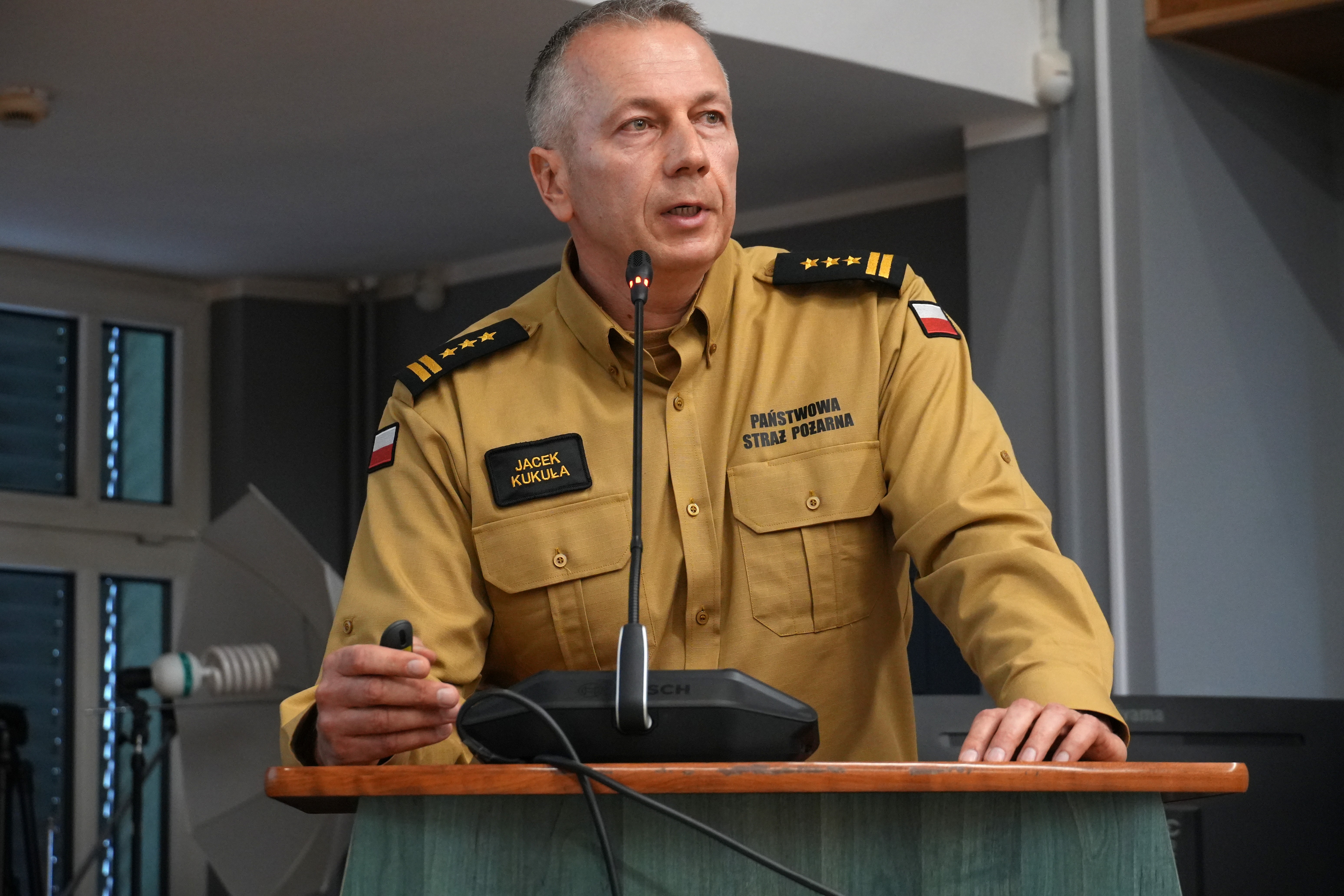 Mężczyzna w mundurze strażackim przy mównicy 