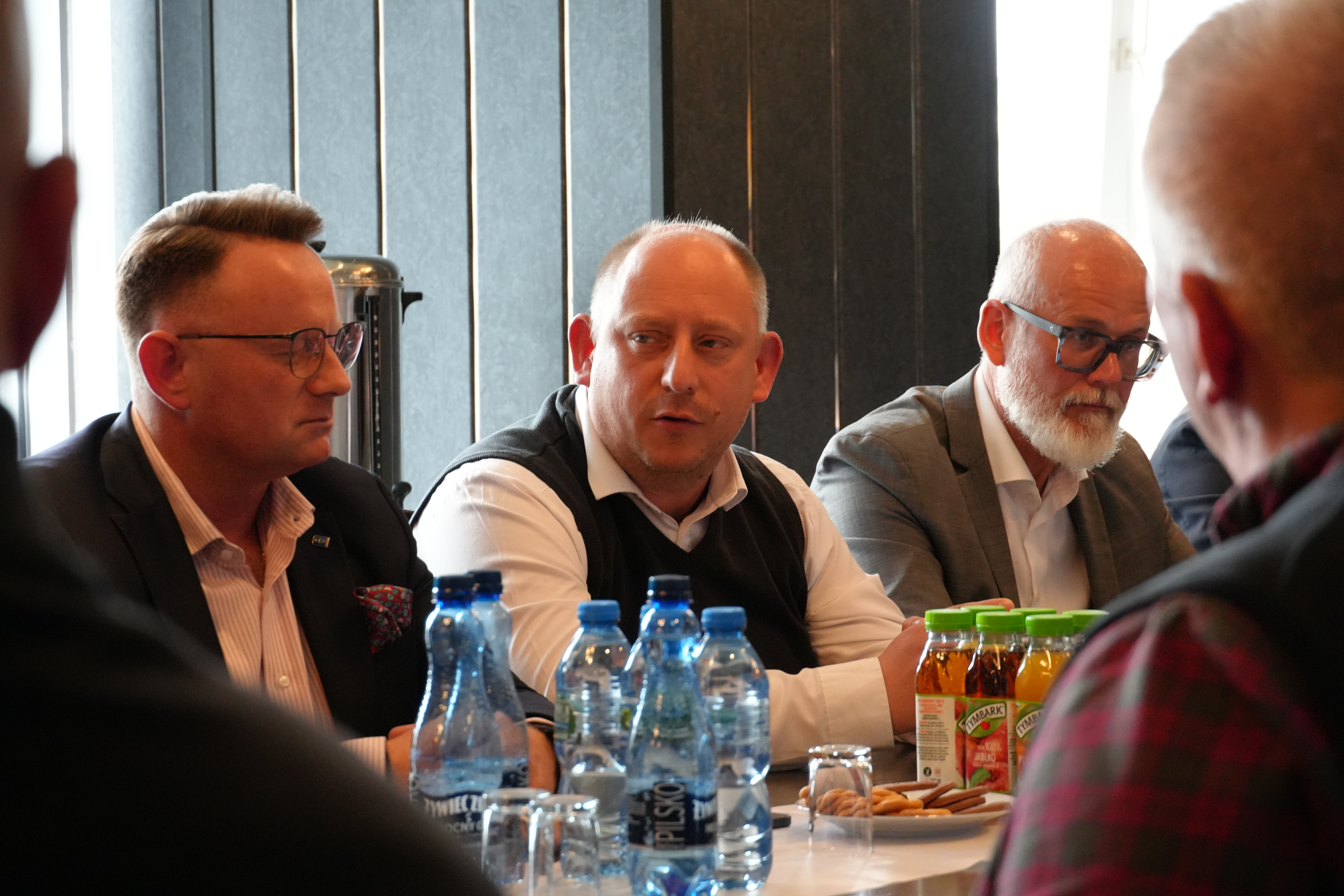 Zdjęcie kilku mężczyzn siedzących przy stole i rozmawiajacych.