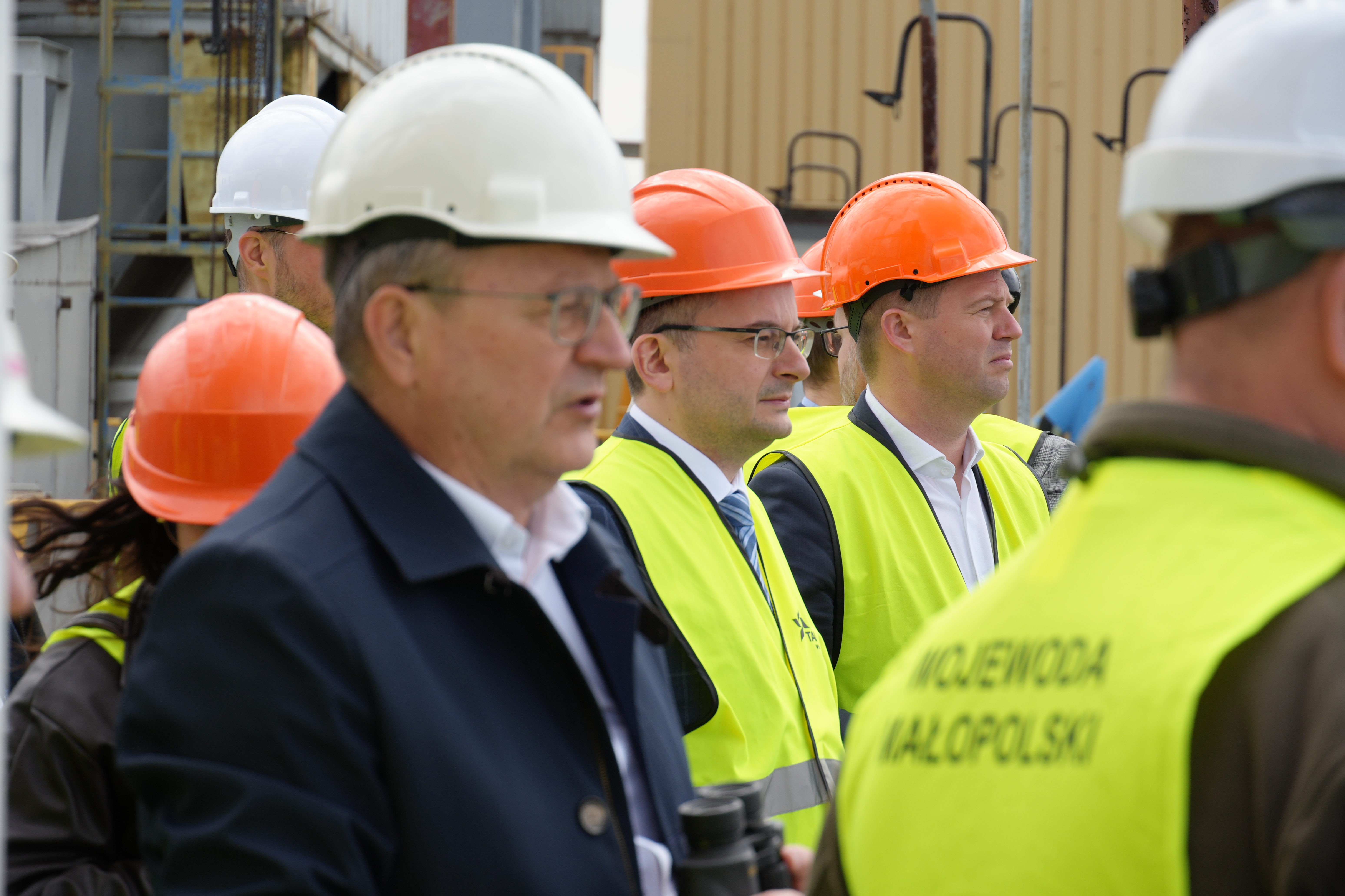 Zdjęcie kilku osób w kasach i kamizelkach odblaskowych obserujących otoczenie.