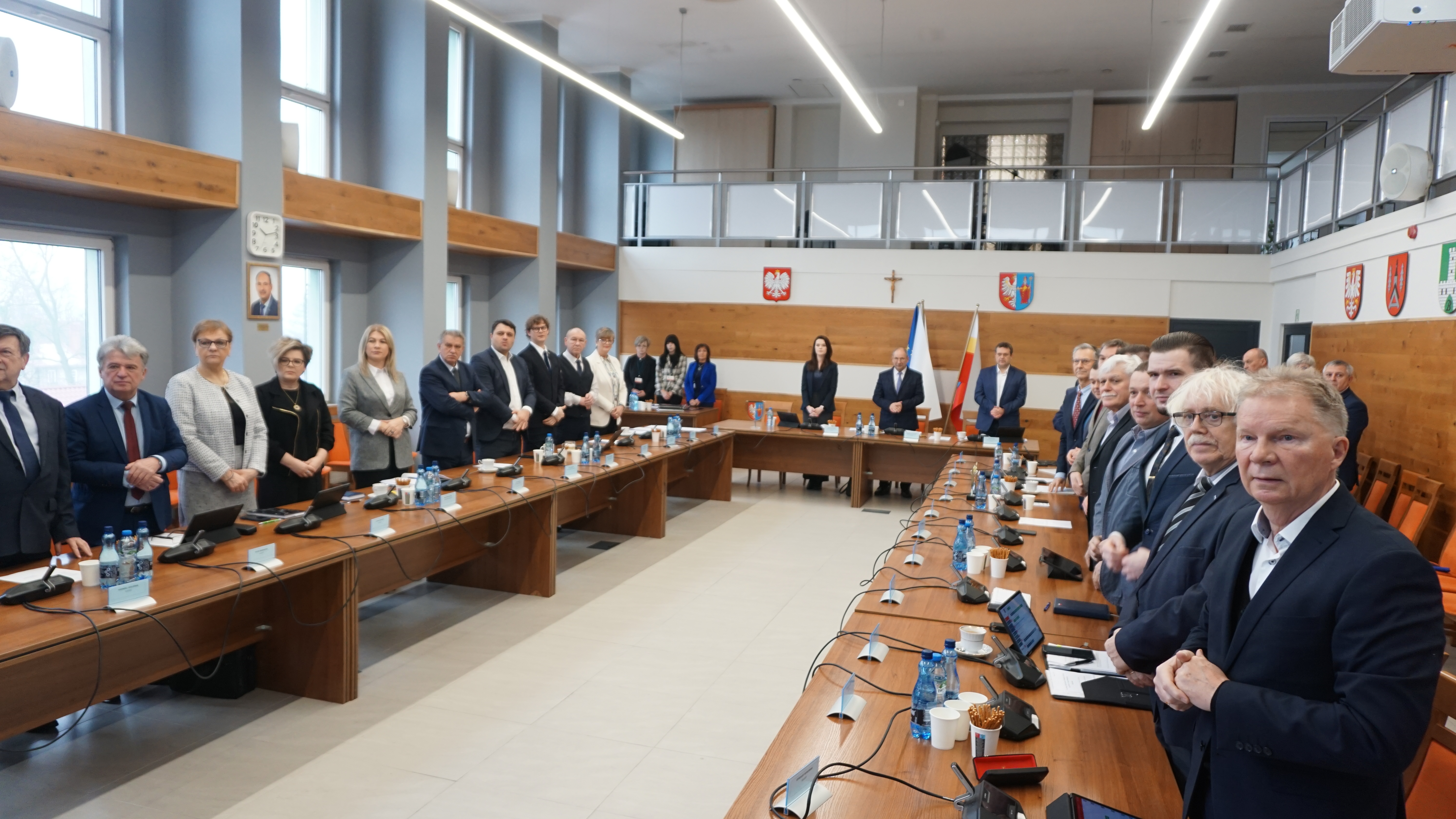 Zdjęcie kilkudziesięciu radnych bijących brawa dla odznaczonego.