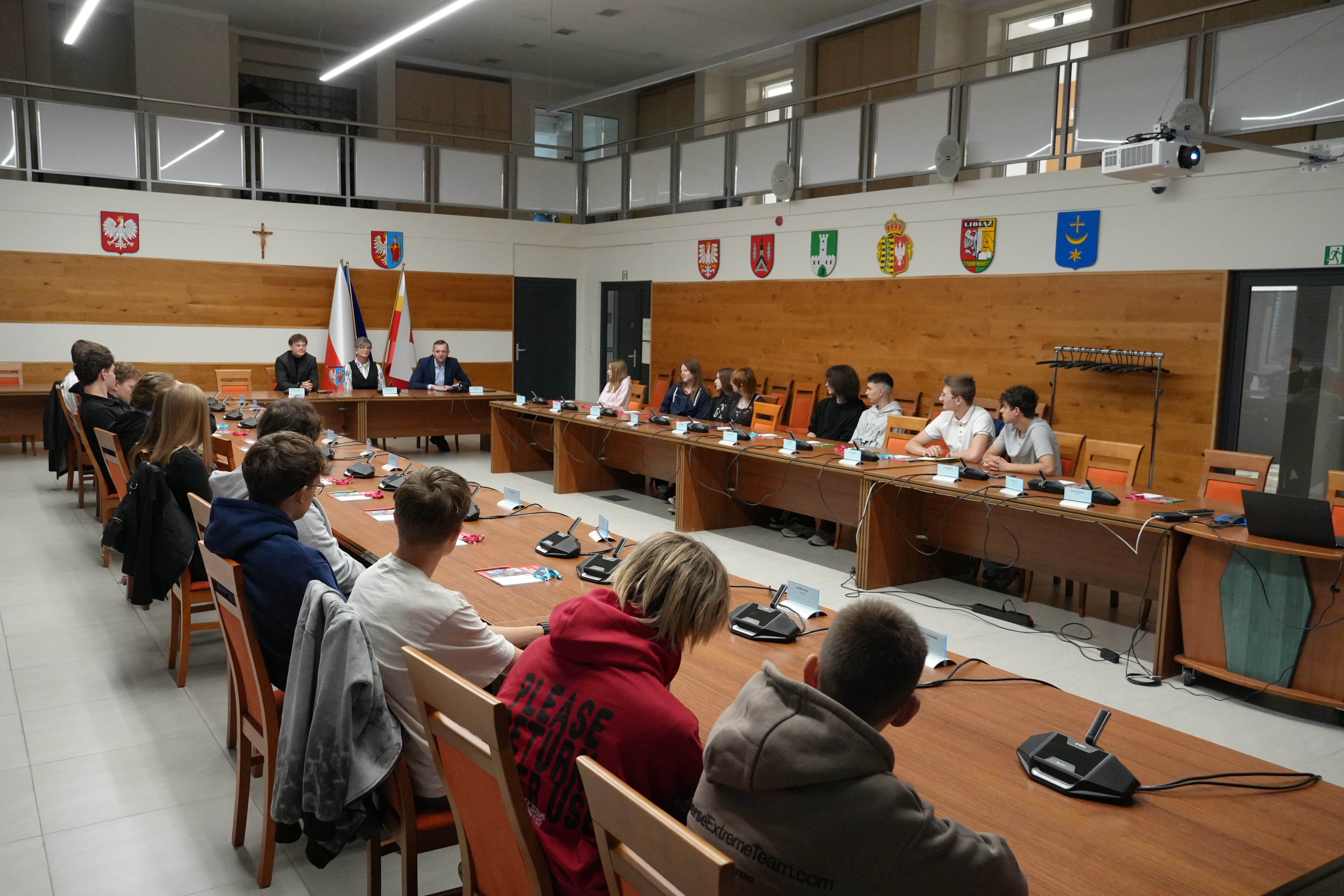 Zdjęcie kilkudziesięciu osób siedzących przy stołach na dużej sali narad.