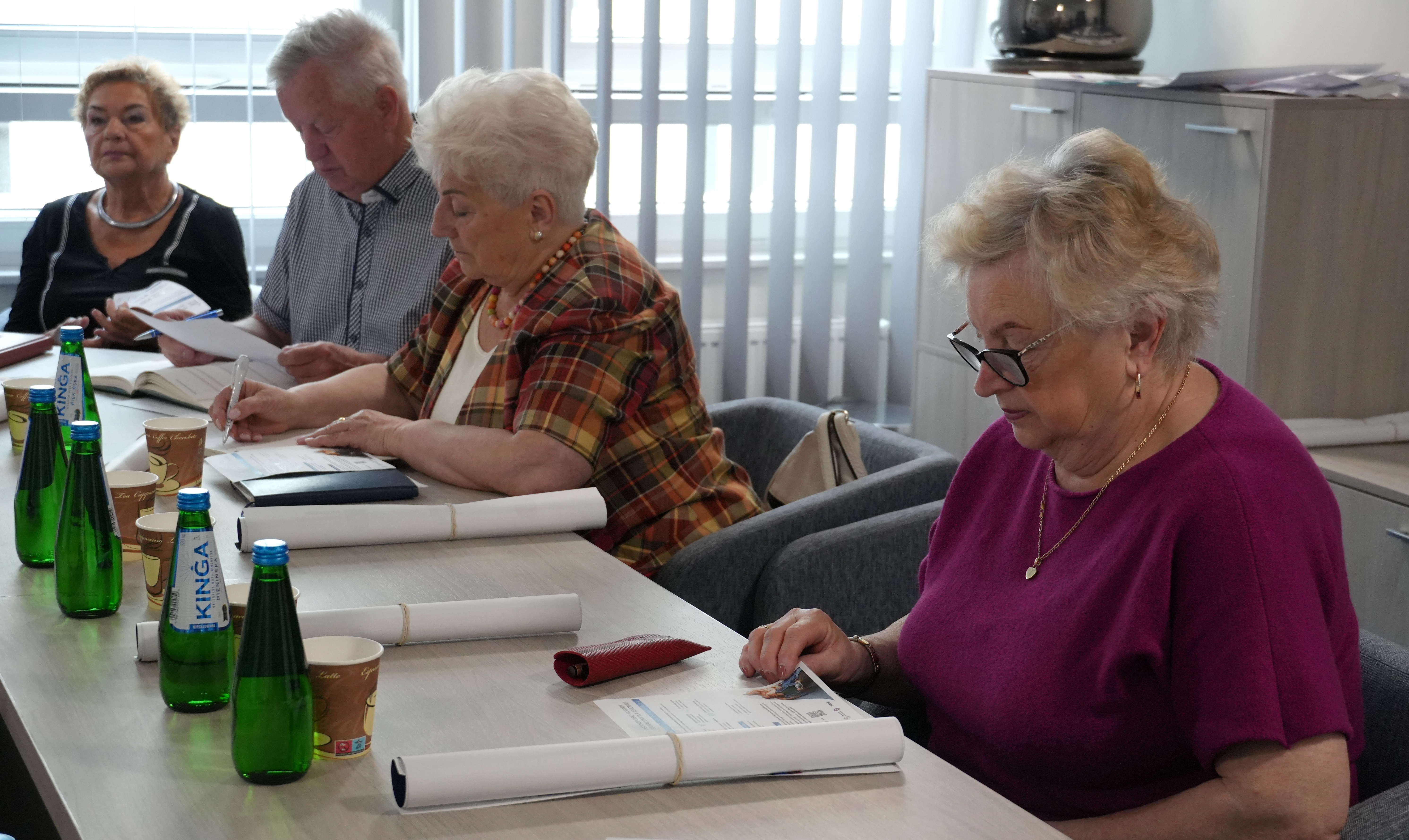 Seniorzy siedza przy stole i rozmawiają