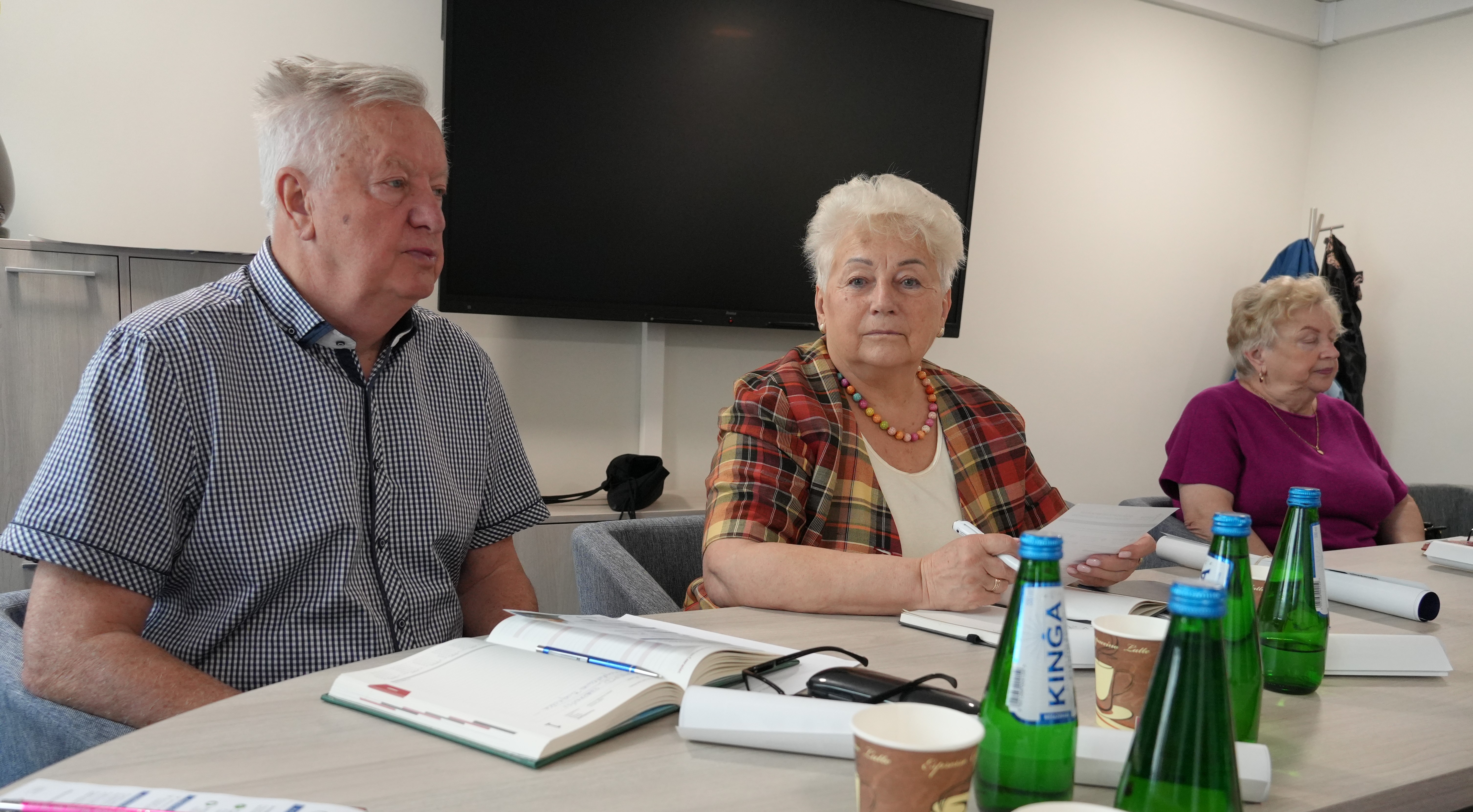 Seniorzy siedza przy stole i rozmawiają