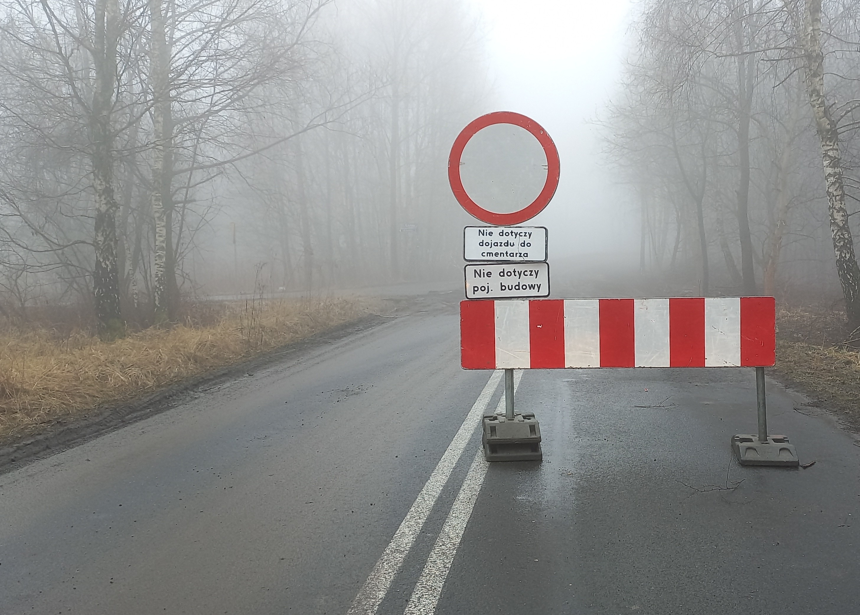 Zdjęcie drogi na której stoją znaki komunikujące o zamknięciu drogi oraz objeździe. 