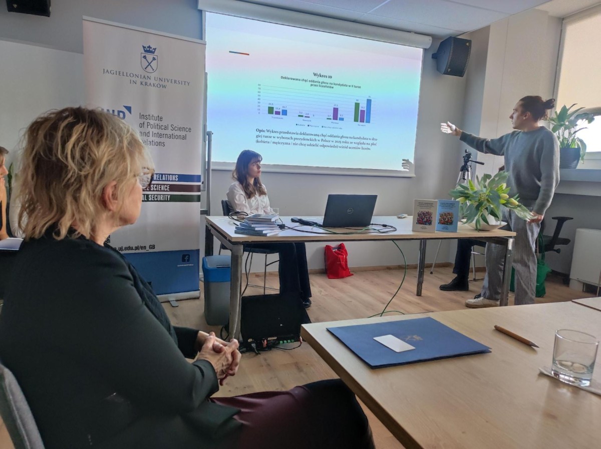 Zdjęcie dwóch osób omawiający prezentacje wyświetlaną na ścianie za nimi. 